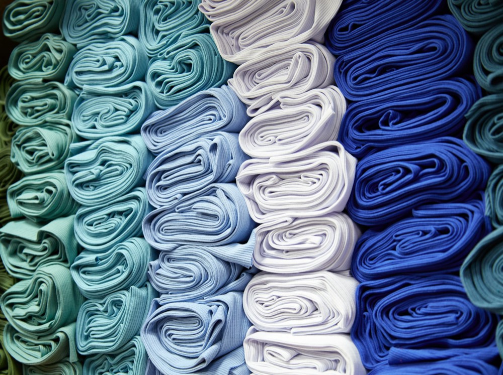 Rolled bolts of fabric stacked on a shelf