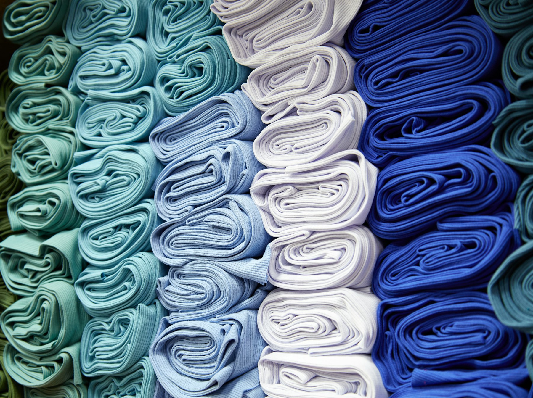 Rolled bolts of fabric stacked on a shelf